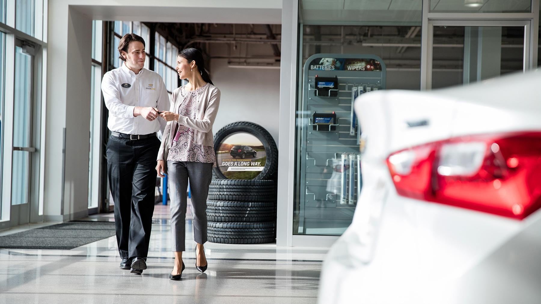 Customer and dealership staff walking through a car showroom