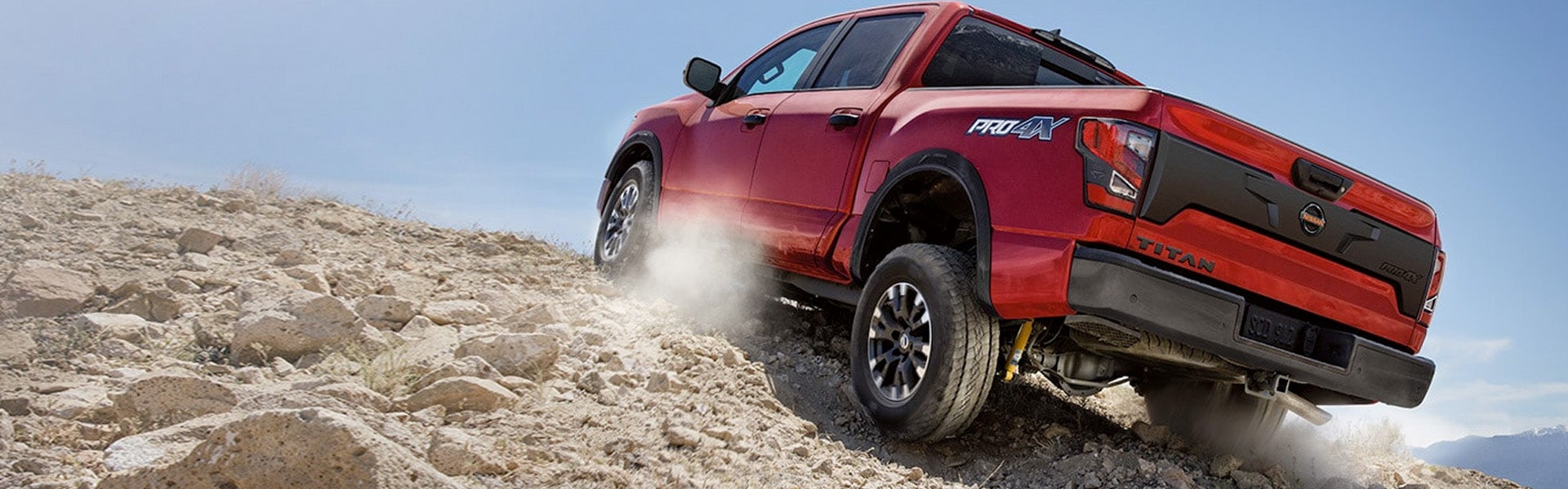 Red Nissan Titan truck driving on rocky terrain