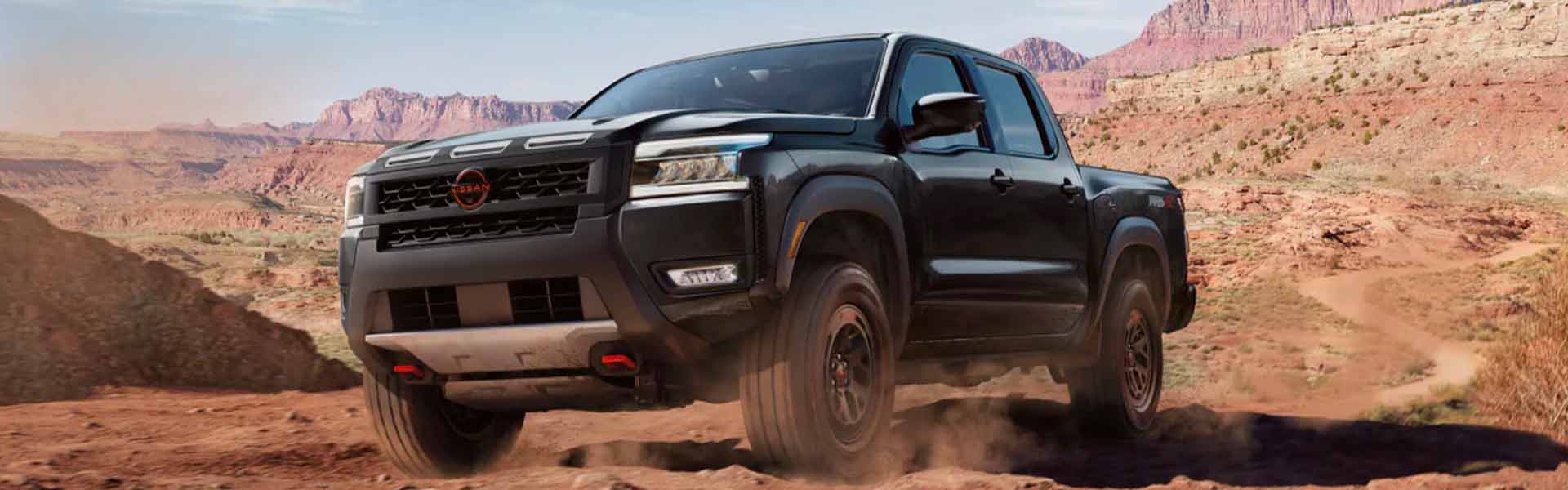 Black Nissan truck driving through desert terrain