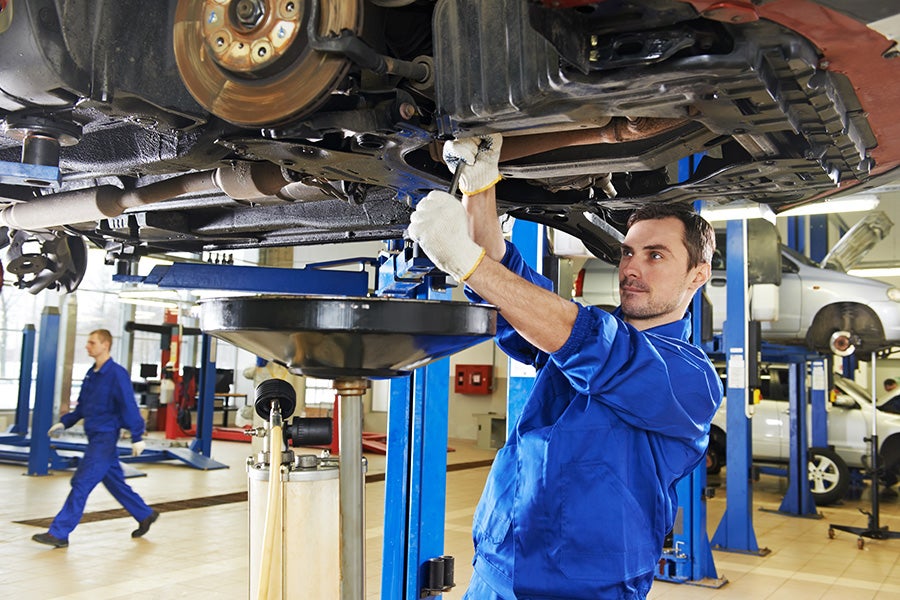 Mechanic performing a multi-point inspection on a car lifted in the service bay